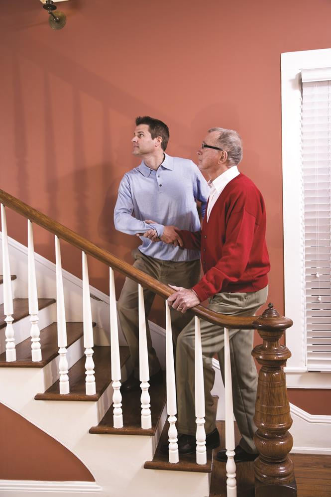 Man helping senior father climb staircase at home